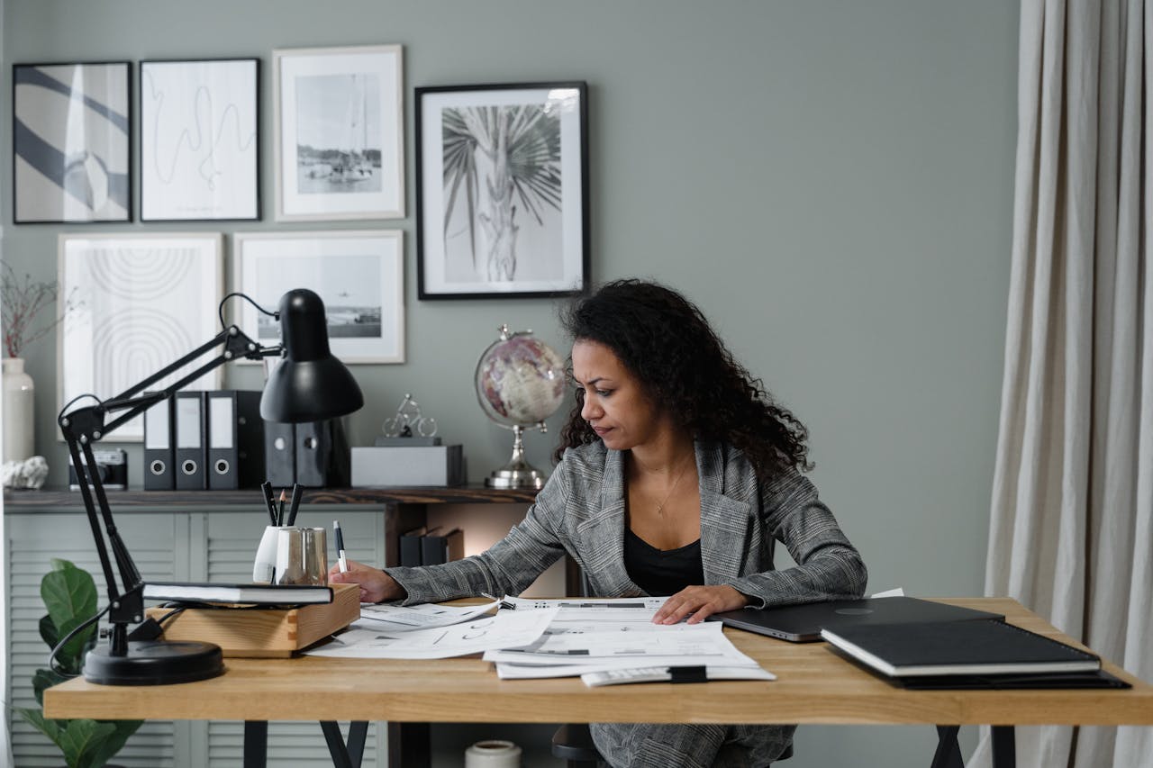 Businesswoman evaluates documents at a modern desk in a stylish office setting.